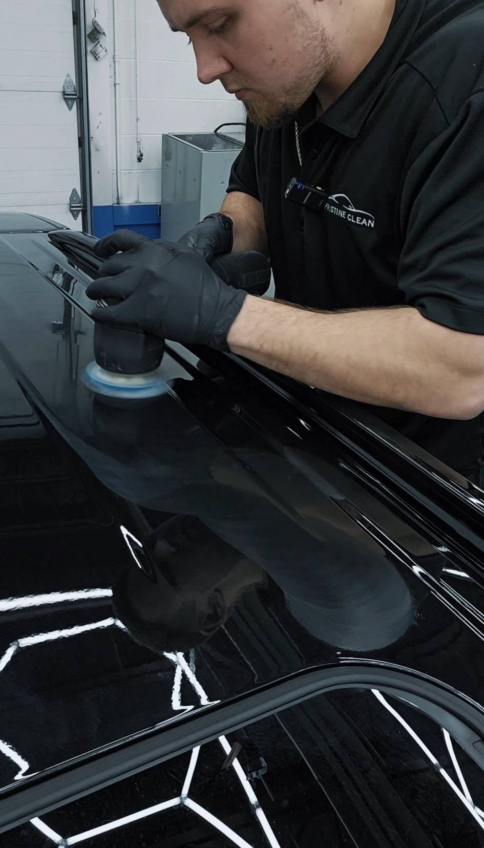 Gerard machine polishing black paint under the inspection lights at Pristine Clean